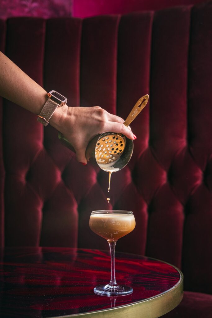 City Style and Living Magazine Winter 2025 Impress Guests with This High Rolling Espresso Martini poured into glass hand with velvet backdrop