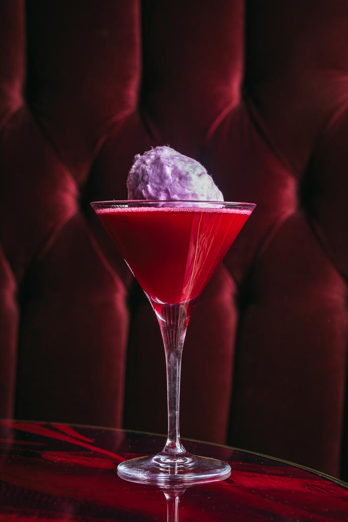 City Style and Living Magazine Winter 2025 cotton Candy Martini in glass in front of red velvet chair